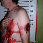 A picture of a shirtless man covered in blood