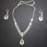 A picture of a shiny silver necklace and a pair of earrings