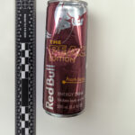 A picture of a dented Redbull Peach can.