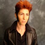 A picture of a person with orange hair and a dark background