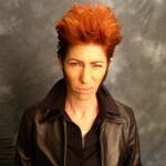 A picture of a person with orange hair and a dark background