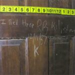 A picture of door with writing scratched into it.