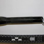 a picture of a dirty flashlight taken near a measuring ruler