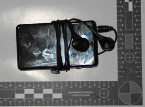 A picture of an mp3 player taken near a measuring stick.