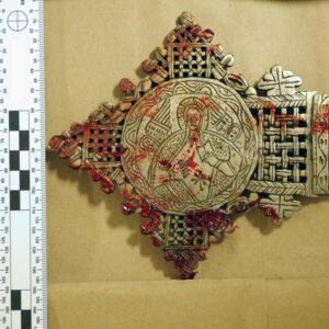 Bloodied tip of gold religious item.