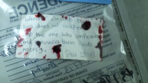 Note card with writing and blood inside a plastic evidence bag