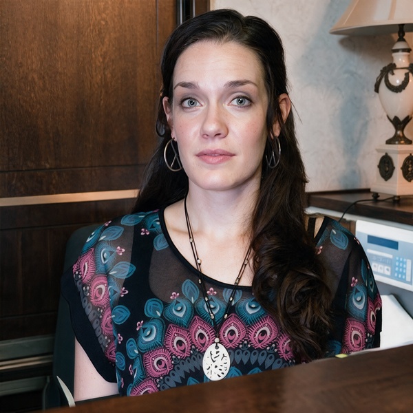 Woman with long dark hair sitting behind a reception desk