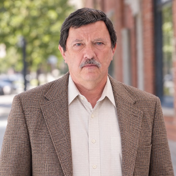 Man with dark hair and a salt-and-pepper mustache