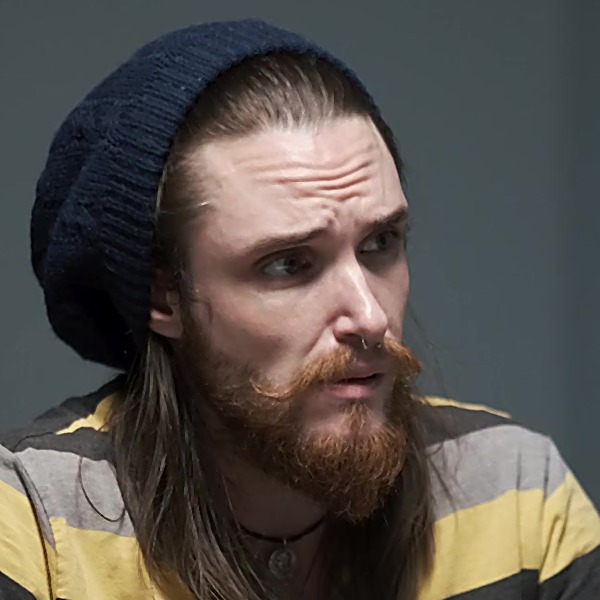Young man with long dark hair and scruffy beard, looking worried