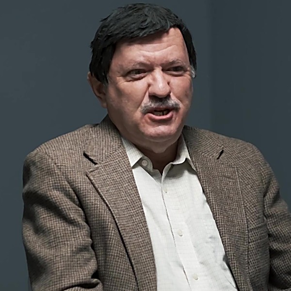 Man with dark hair and a salt-and-pepper mustache, looking frustrated