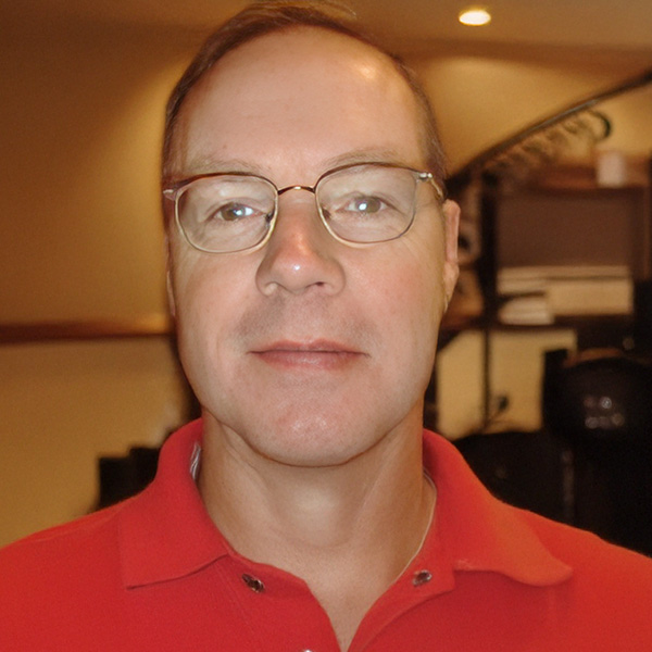 Slightly smiling man with glasses and short, receding brown hair