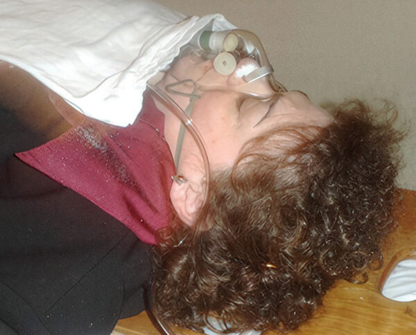 Woman on a gurney with an oxygen mask on her face