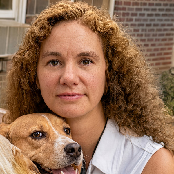 Woman with long dark curly hair holding a dog