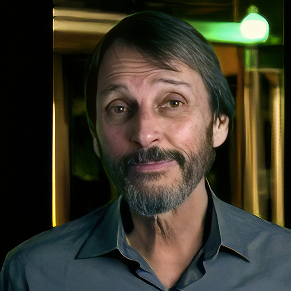Slightly smiling man with dark hair, moustache, and beard
