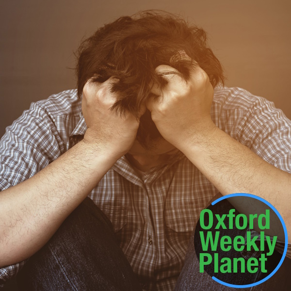 Man with his head down and his fists clenched in his hair